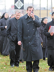 Archbishop Allen Vigneron uses a wireless microphone to lead the recitation of the rosary as the prayer vigil participants walk along Eight Mile Road.